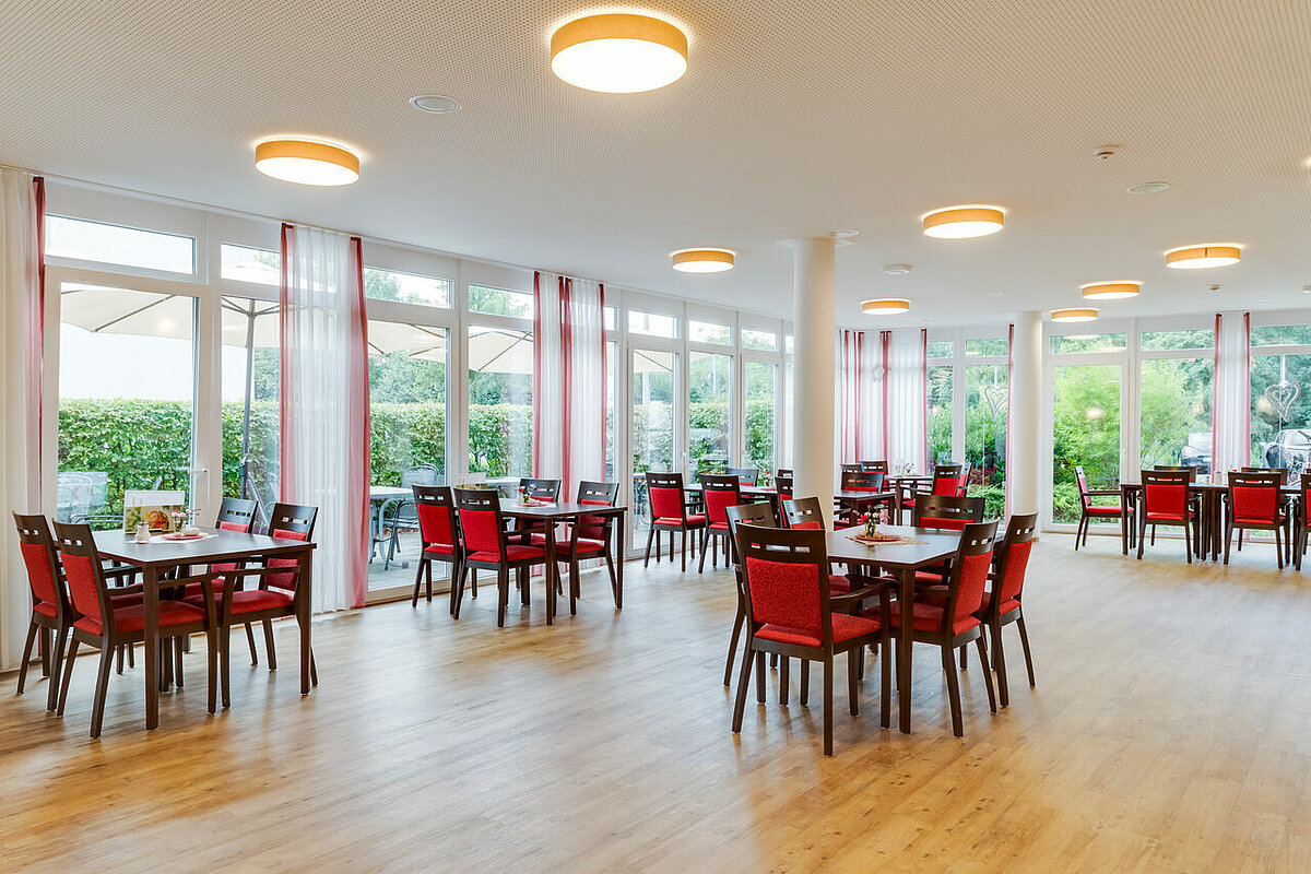 Restaurant mit Tischen und roten Stühlen im Pflegeheim Vechelde