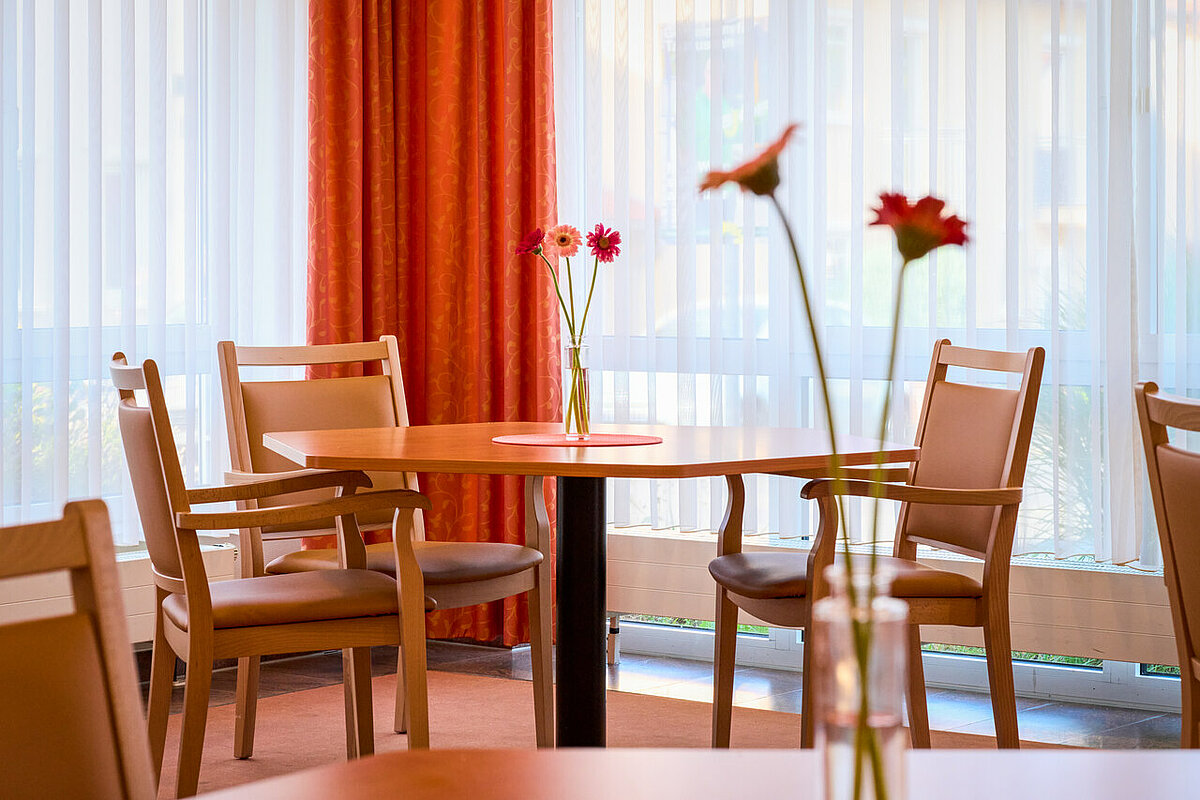 Tisch mit drei Stühlen und Blumen im Seniorenheim