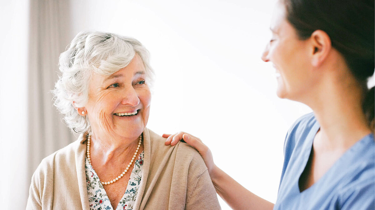 Lächelnde Seniorin mit Pflegekraft im Seniorenheim von CMS