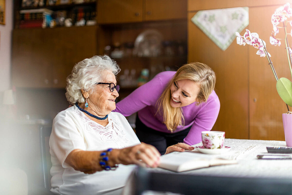 Mitarbeiterin im Bundesfreiwilligendienst redet mit Seniorin im Pflegeheim